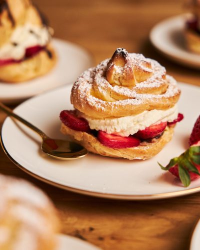 A closeup shot of delicious cream puff with strawberries on a wooden table