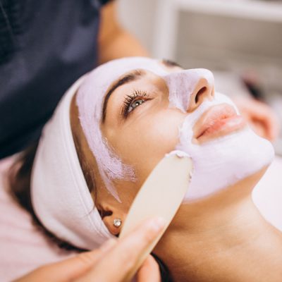 cosmetologist-applying-mask-face-client-beauty-salon