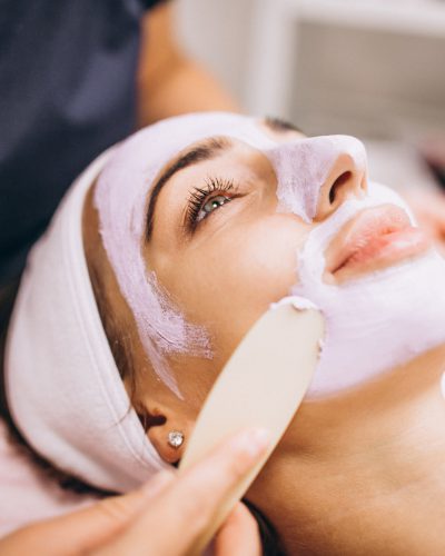 cosmetologist-applying-mask-face-client-beauty-salon